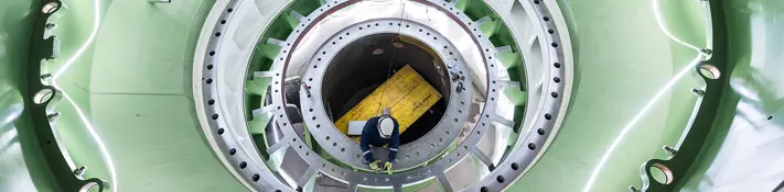 Ein Blick ins Innere eines Kraftwerks – ein Mitarbeiter arbeitet an der Turbine.